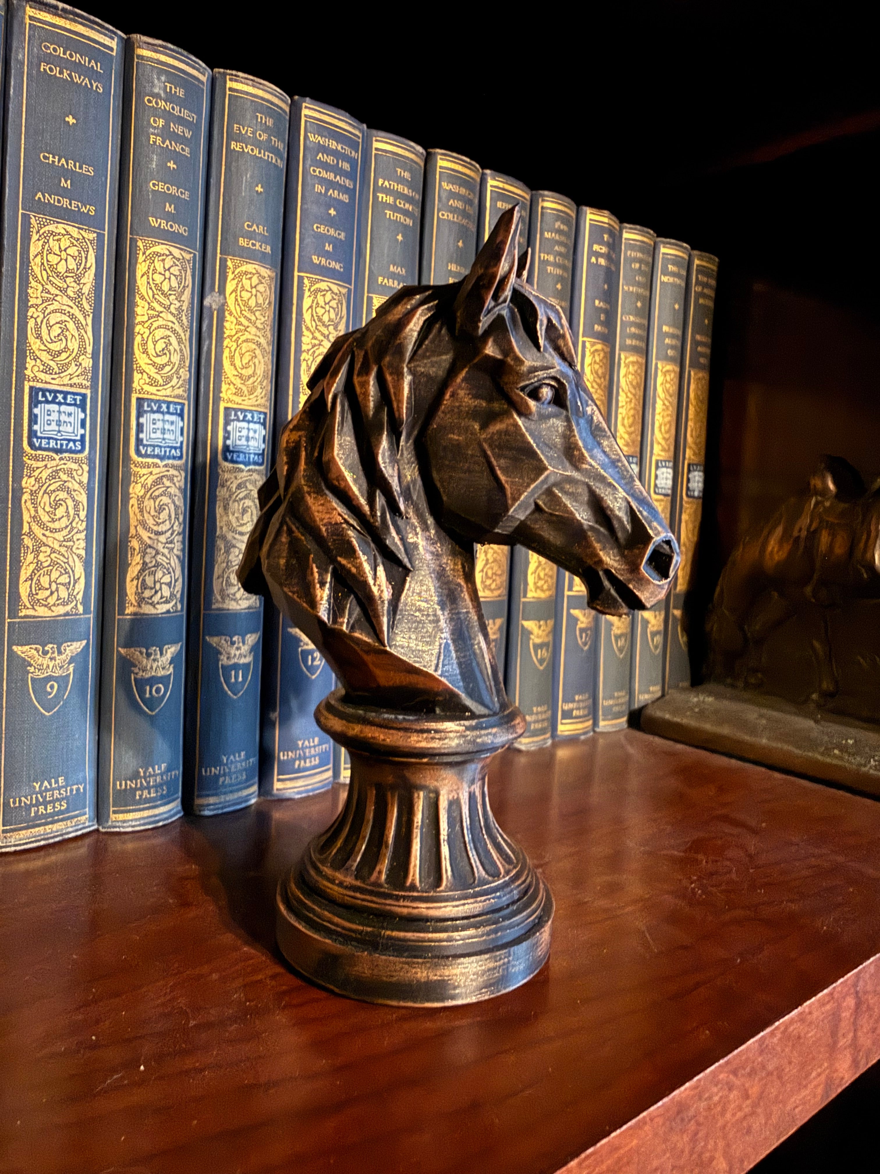 Bronze-finish geometric horse bust displayed beside vintage books.